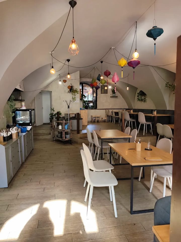 Interiér olomoucké pobočky s klenbou, dřevěnými stoly a barevnými lampiony